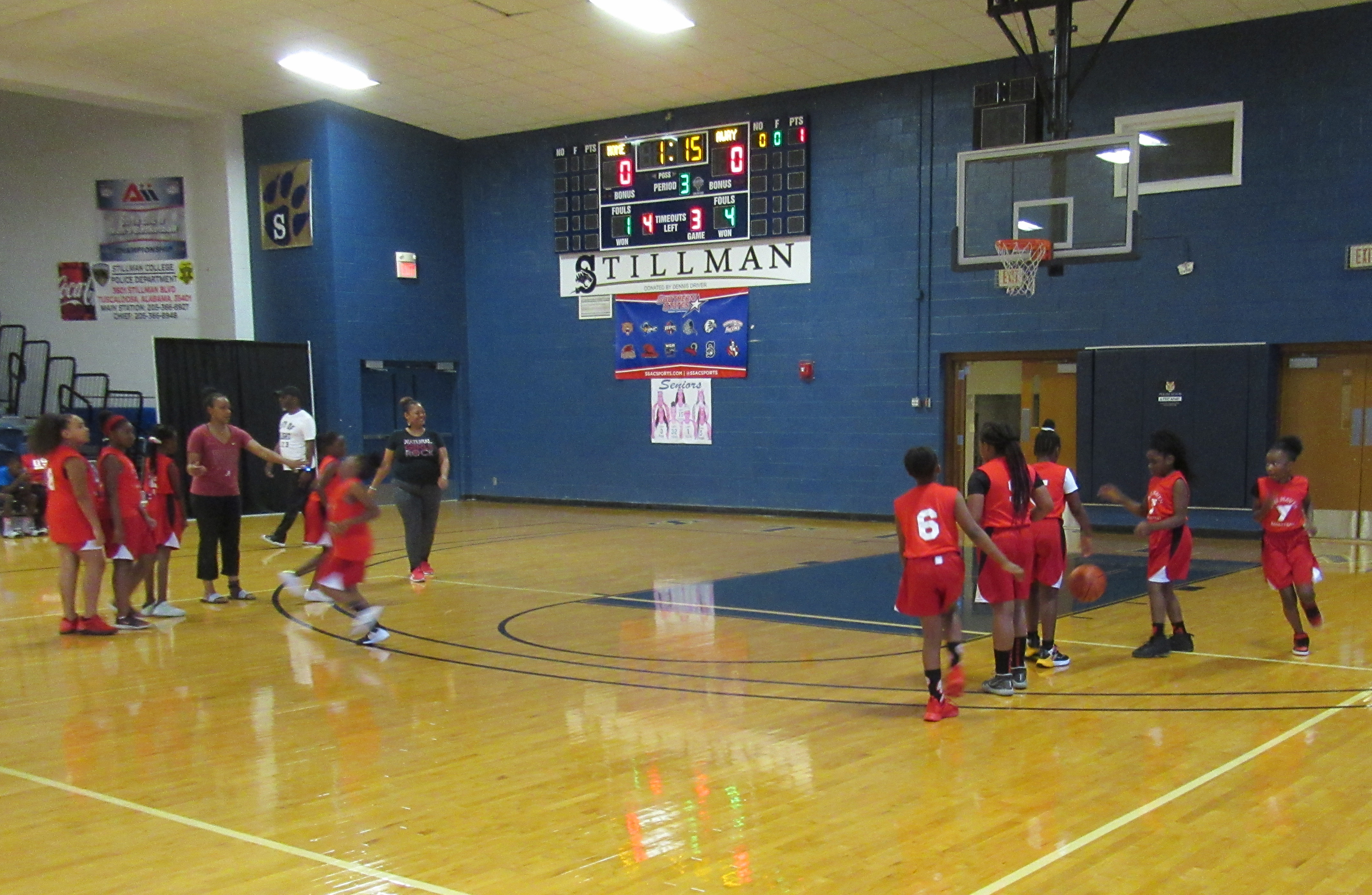 A group of black children play basketball on an indoor court