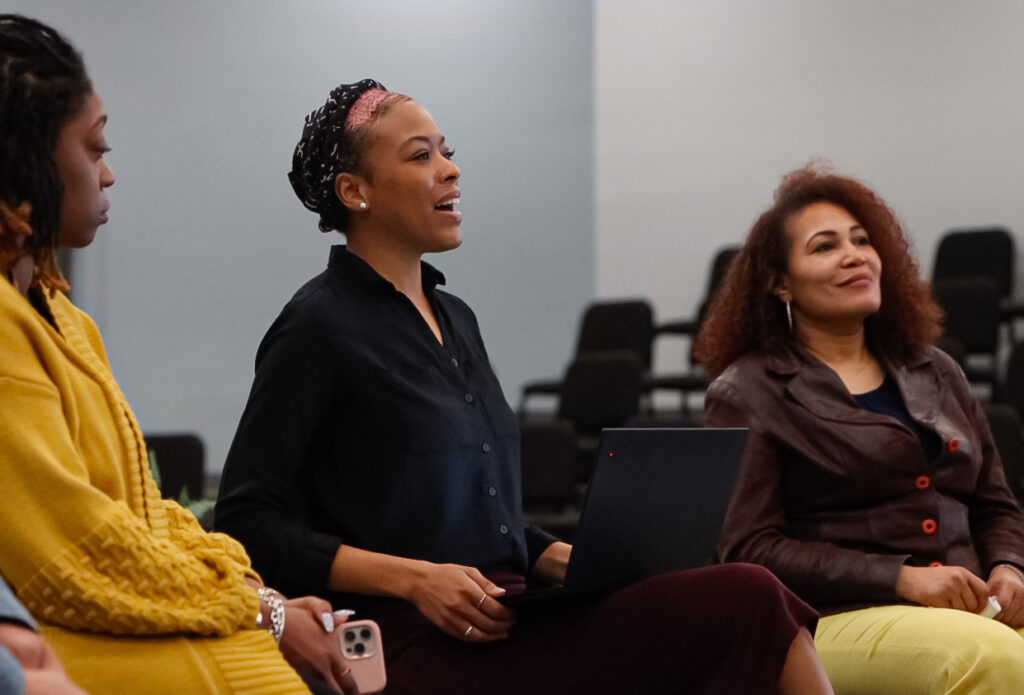 Three black women deliver a lecture on a college campus