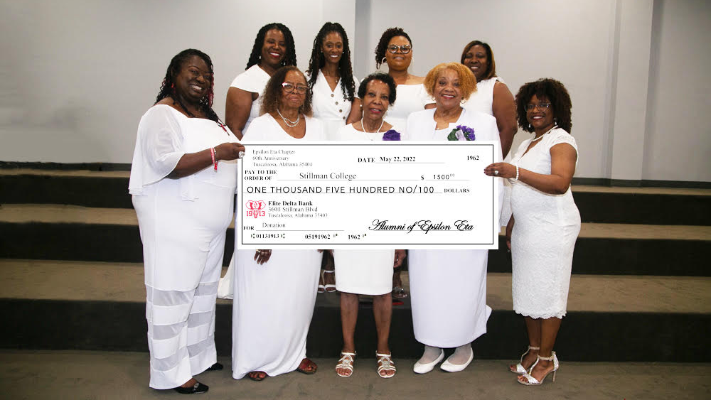 A group of black women pose for a photo while holding a check