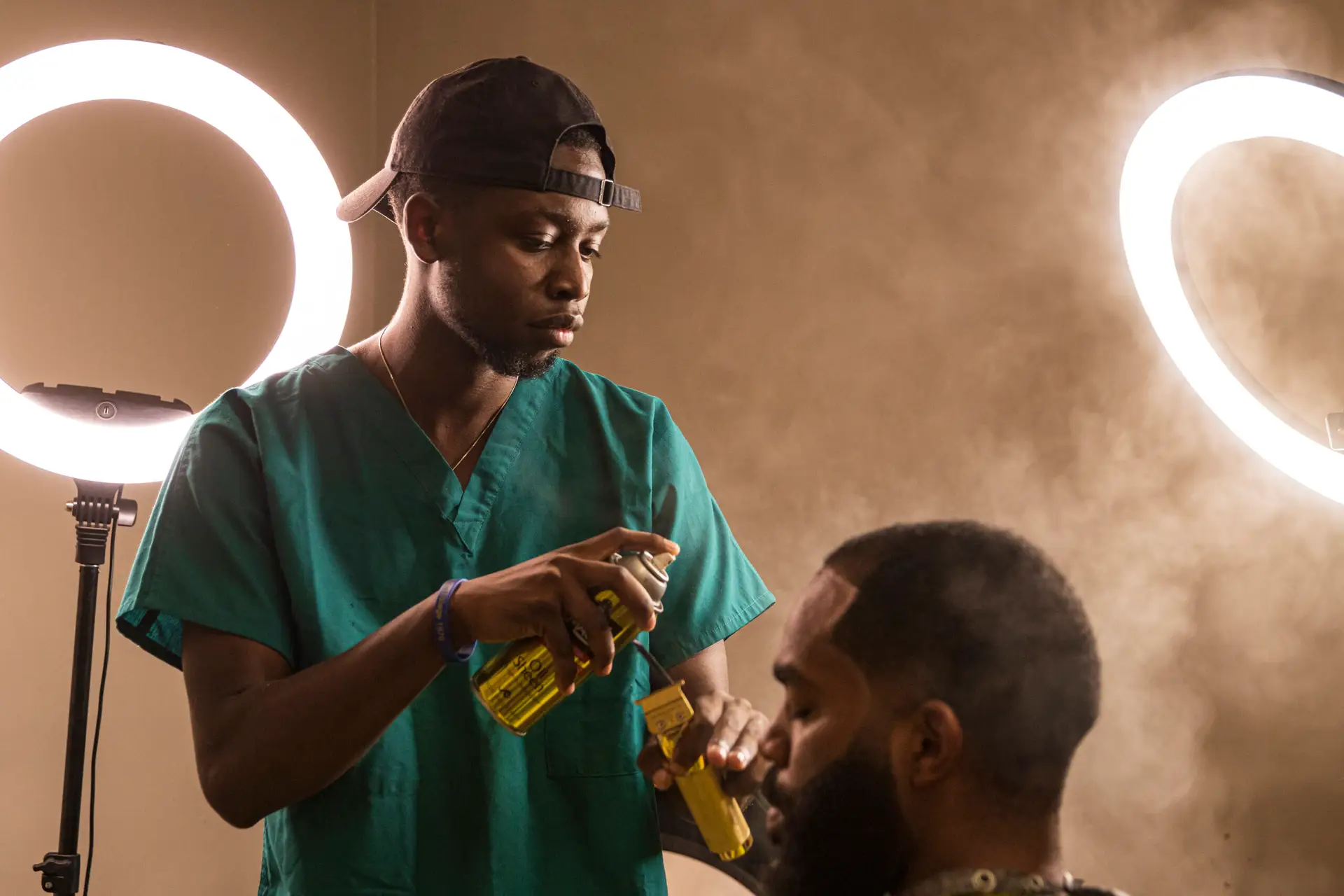 A black barber applies hair spray to a customer's head