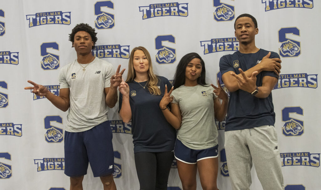 A group of athletes pose in front of a backdrop.