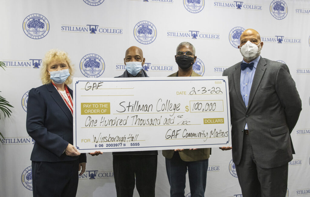 Three black men and a white woman hold an oversized check