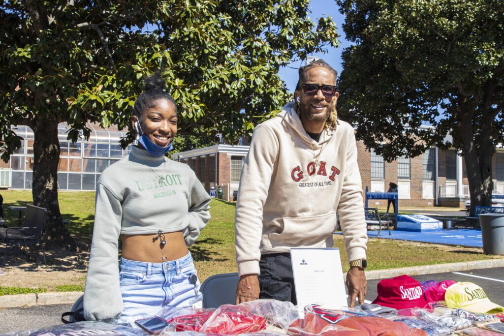A black woman and black man pose for a photo at an outdoor shopping event