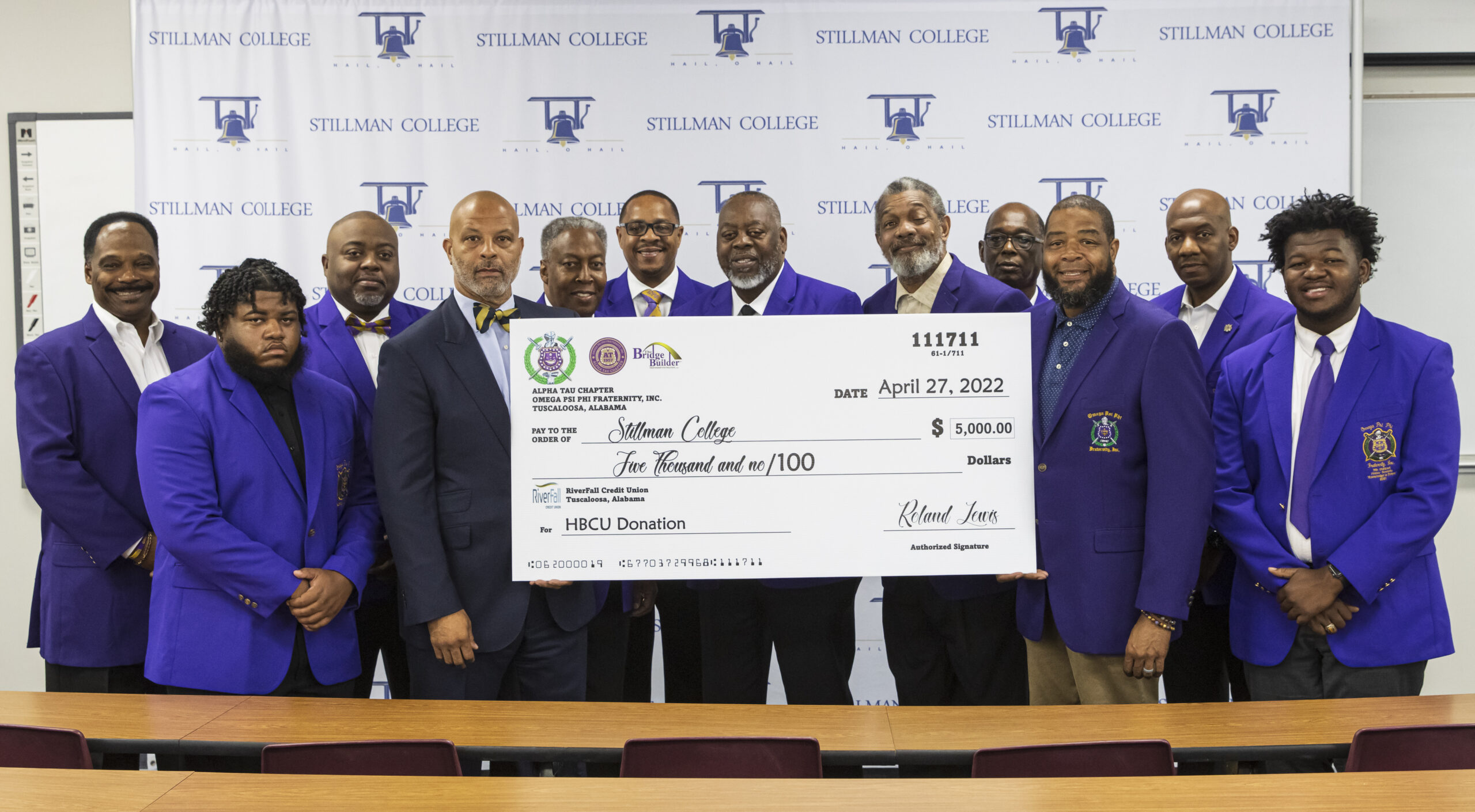 A group of black men pose for a photo while holding an oversized check