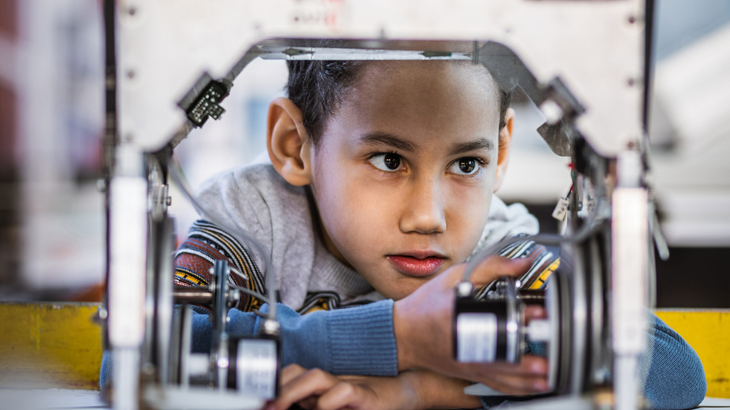a young boy stares at a machine during a robotics class