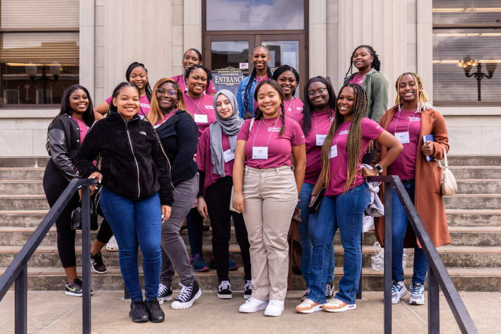 A group of Black female college students pose for a photo in front of a courthouse