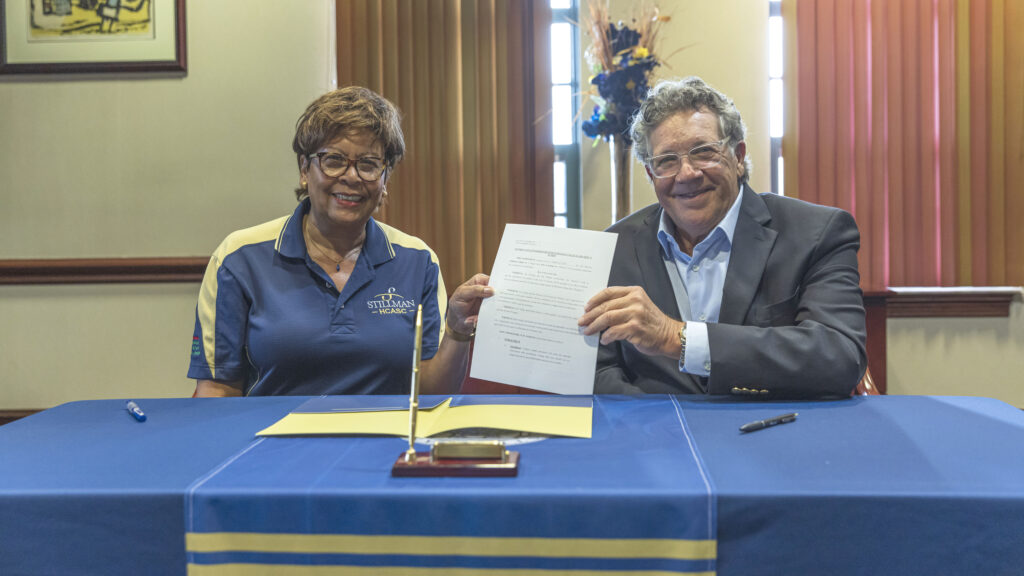 A white man and a black woman hold up a signed agreement