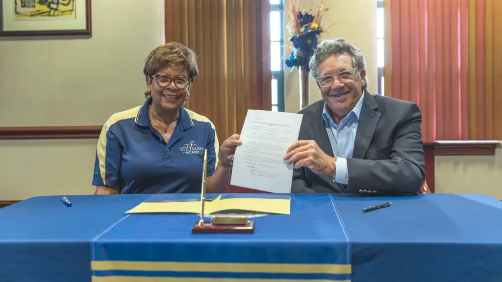 A white man and a black woman hold up a signed agreement