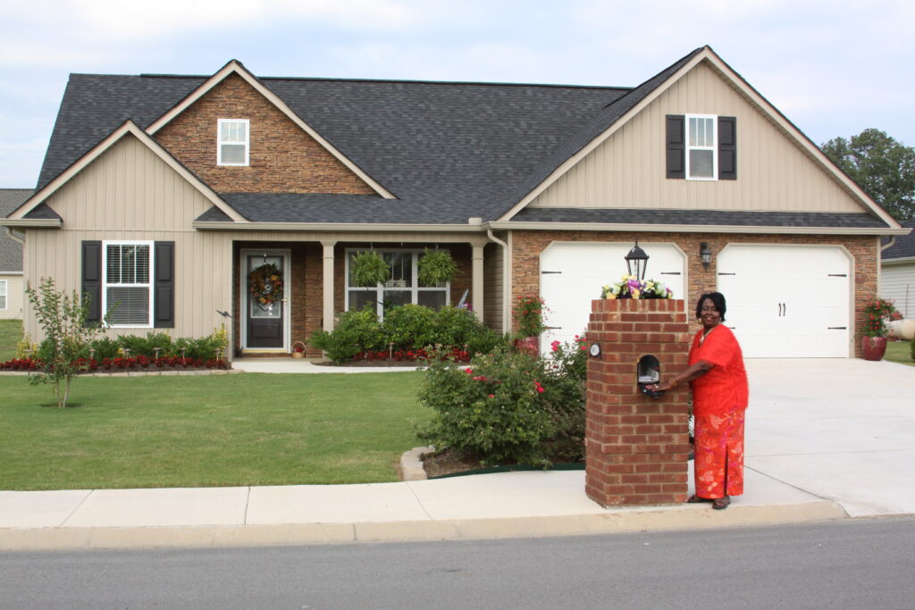 A black woman checks the mail in front of her home