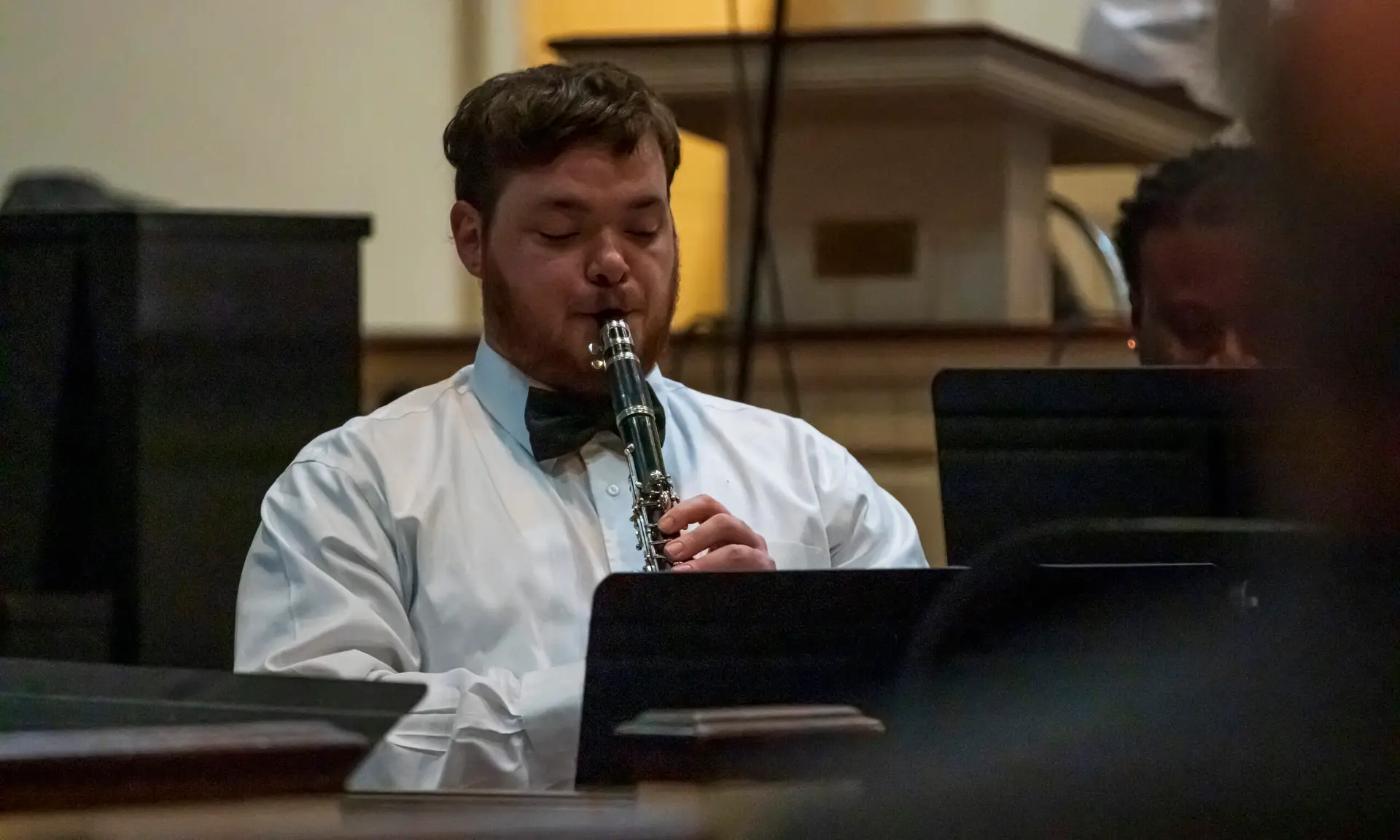 a white male college student plays clarinet in a church