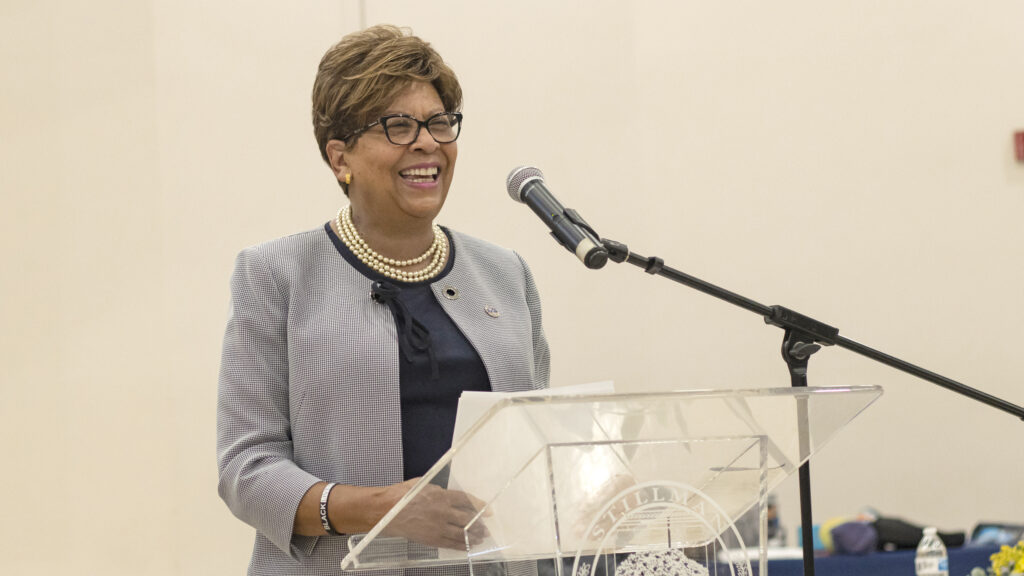 A black female college president speaks at a lectern