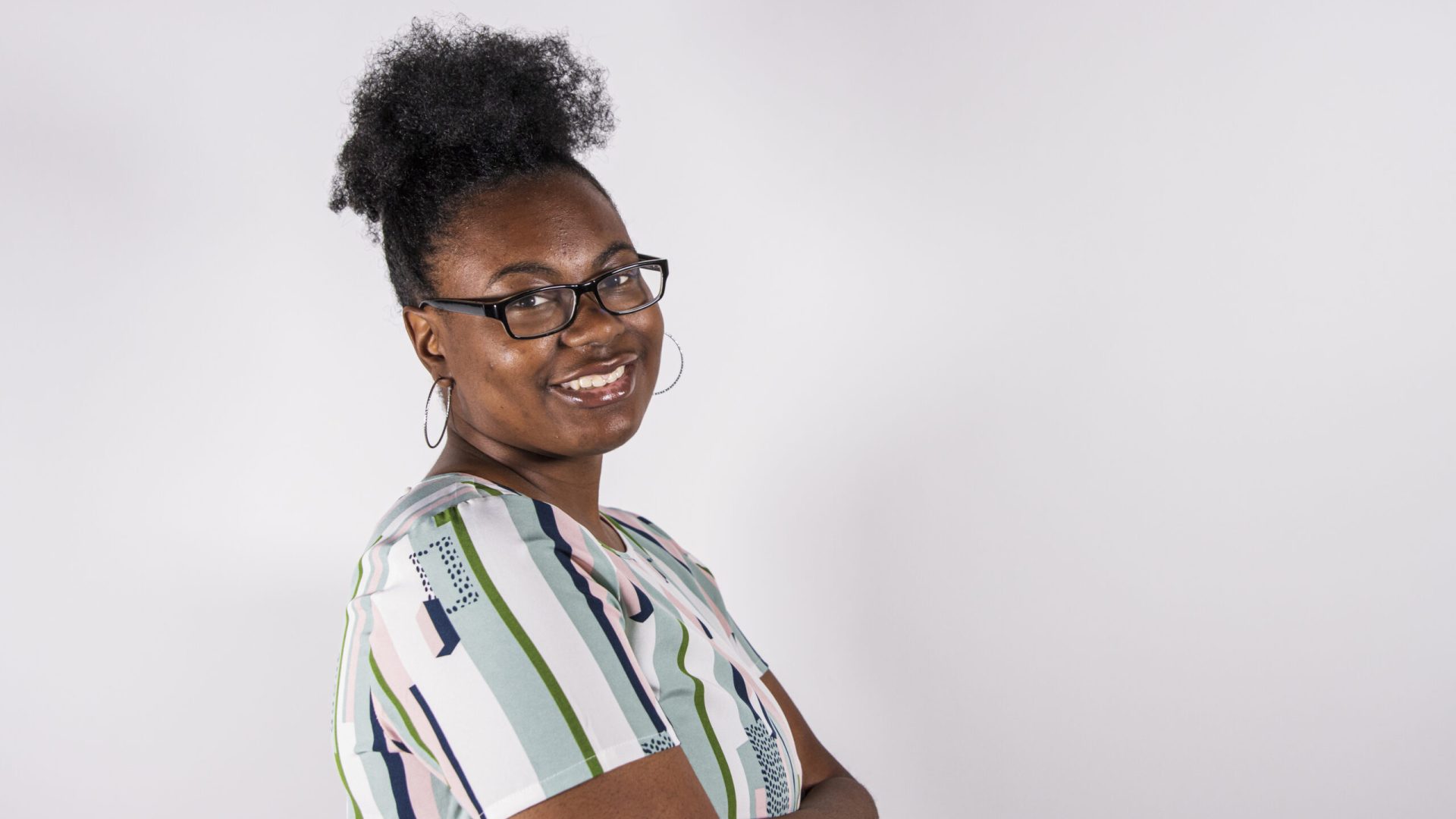 A black female college student poses for a photo in a studio